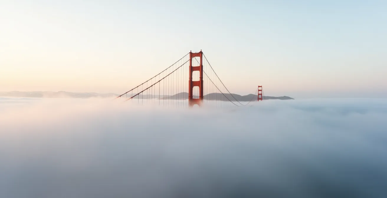 Dramatic view of Golden Gate Bridge towers piercing through fog layer from Marin Headlands viewpoint